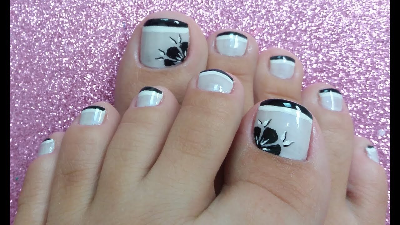 Unhas dos pés decoradas em preto e branco com flor