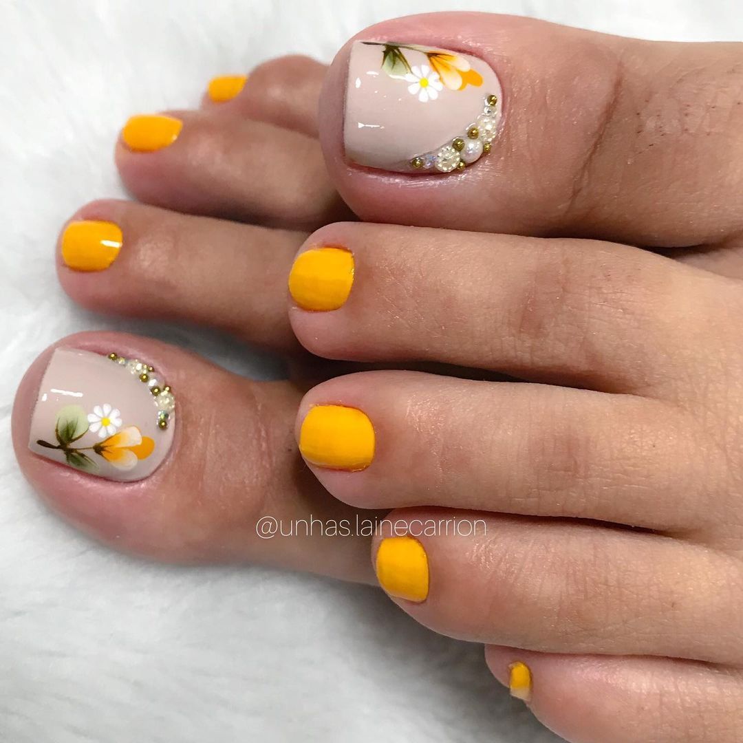 Unha do pé com esmaltação em amarelo e desenhos de flores