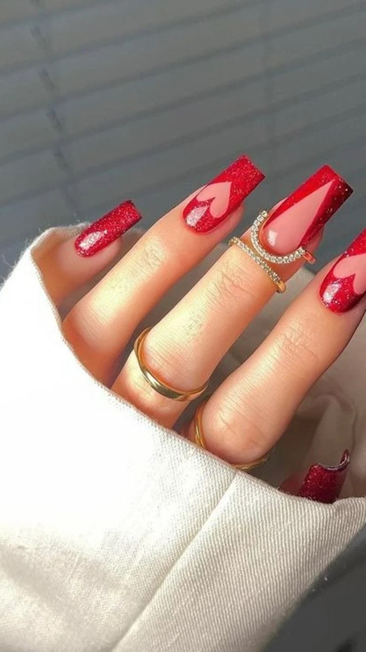 unhas em esmalte vermelho glitter com desenho de coração rosa