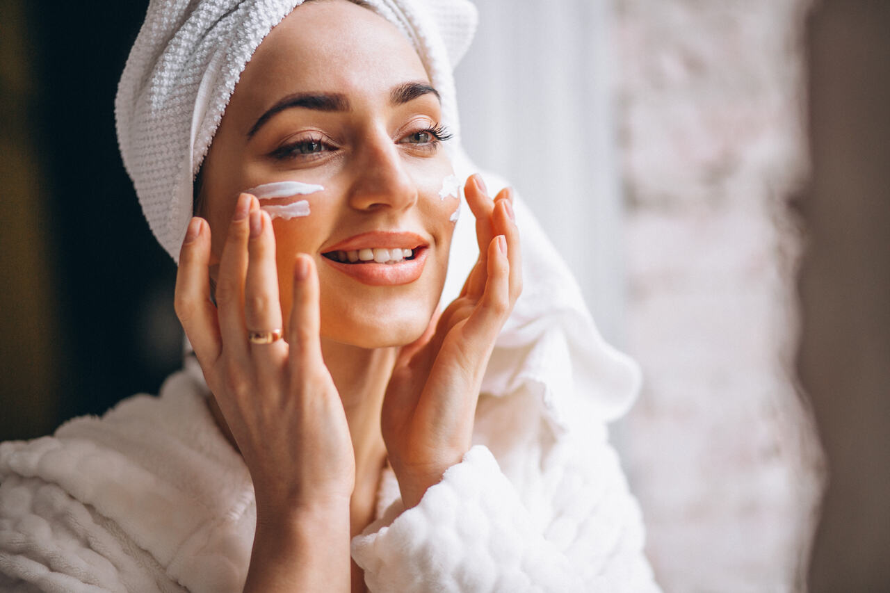 Mulher passa hidratante facial após o banho